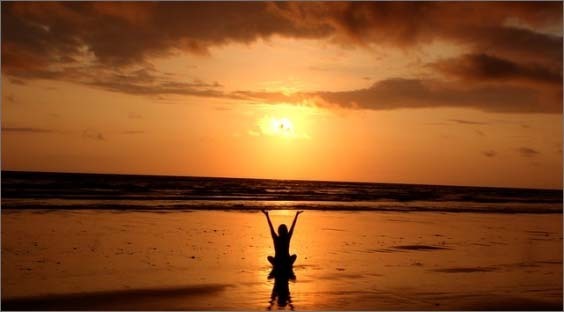 silhouette of person holding up arms on beach